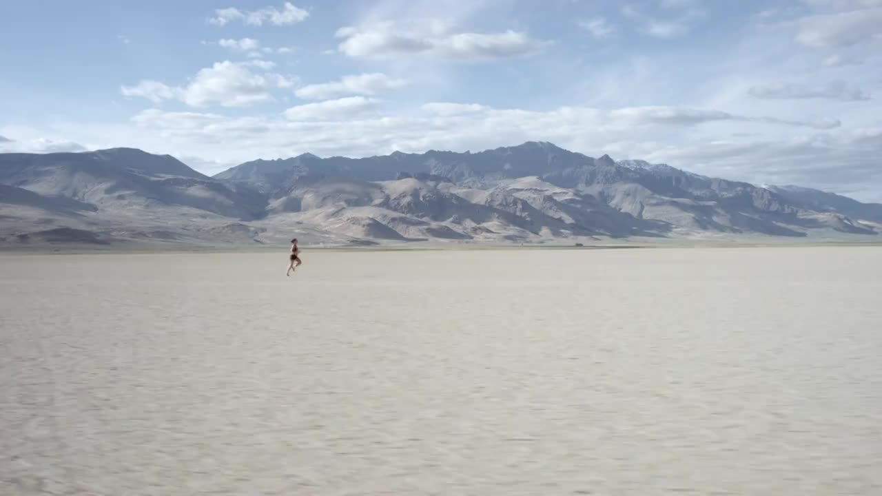 一个女人在沙漠中奔跑的跟踪镜头视频素材