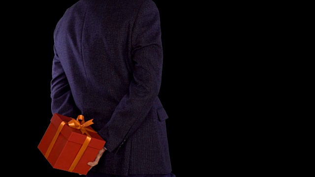一个穿着西装的男人背后拿着一个红色礼品盒。白种男人换脚。商人送礼物。近距离锁定射击。Alpha通道色度键。后视图。视频下载