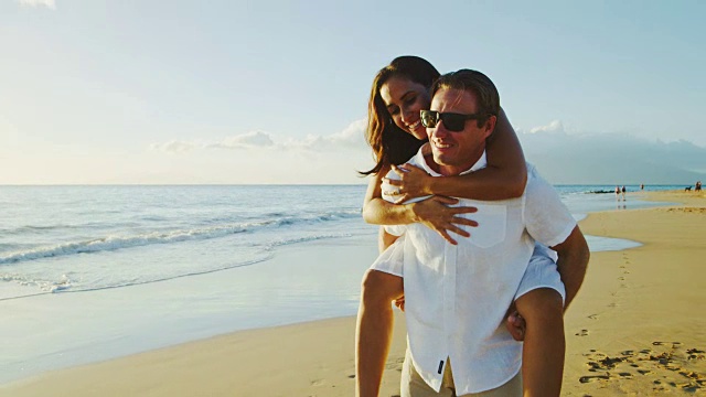 一对情侣在日落时分的海滩上散步视频素材