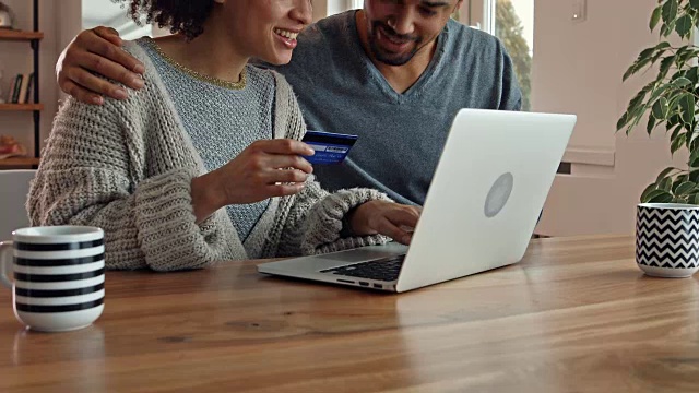幸福的黑人夫妇使用信用卡和笔记本电脑在家里进行网上购物。视频素材