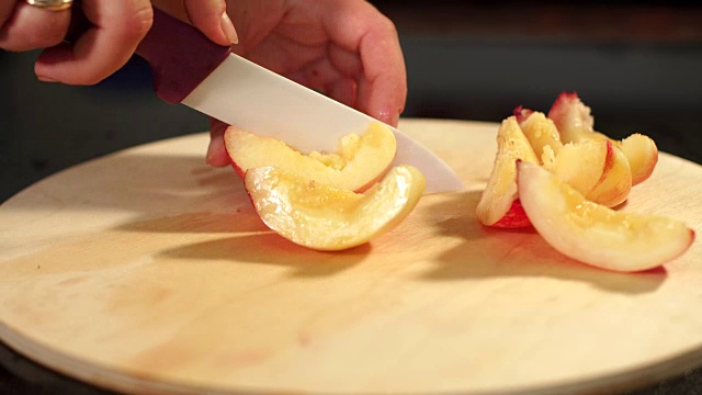 女孩在砧板上切桃子，特写。视频下载