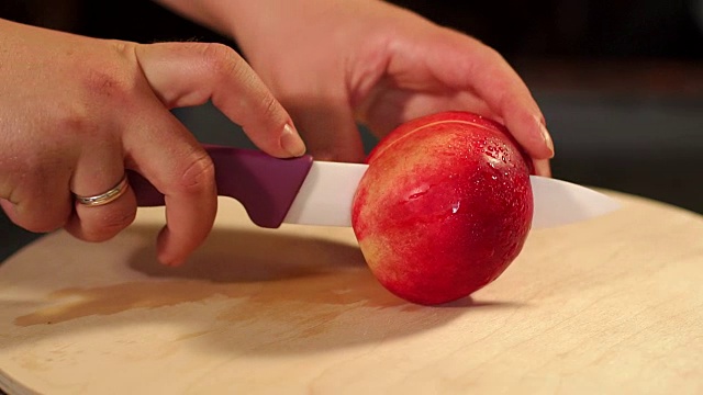 女孩在砧板上切桃子，特写。视频下载