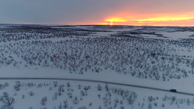 照片:日落时分，汽车在空旷的公路上行驶，穿过风景优美的冬季荒野视频素材