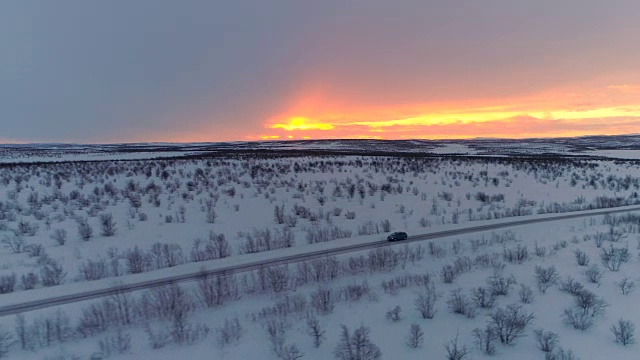 摄影:日出时，汽车行驶在空旷的公路上，穿过风景优美的冬季荒野视频素材