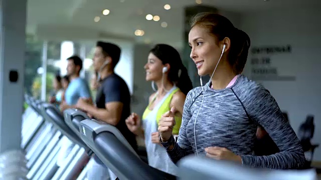 人们在健身中心的跑步机上跑步，看起来意志坚定视频素材