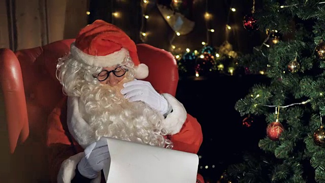 圣诞老人在圣诞树旁阅读新年礼物清单。视频素材