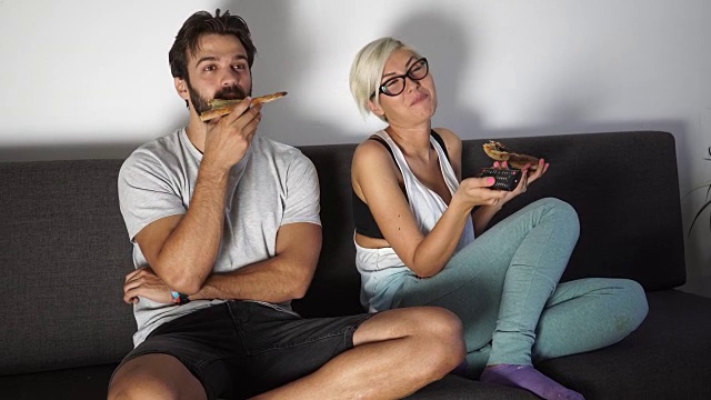 一对夫妇在电视旁吃披萨视频素材