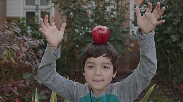 小男孩把苹果放在头上保持平衡视频素材