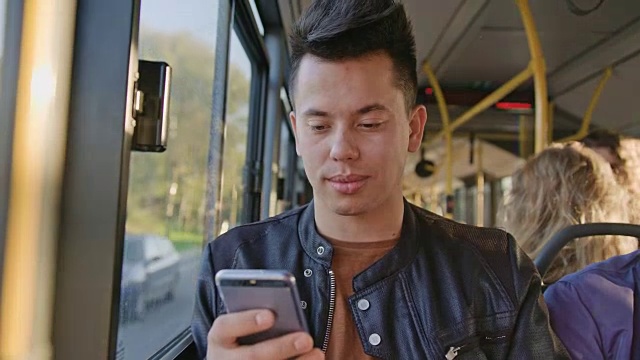 一个年轻人在公交车上用智能手机视频素材