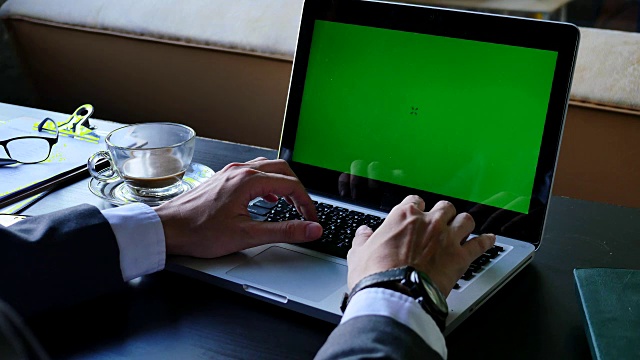 近距离的商人使用绿色屏幕的笔记本电脑在桌子上。视频素材