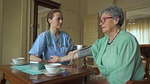 女性家庭护理人员在为一位老妇人测量血压。视频素材