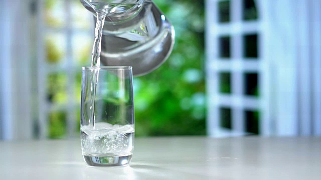 特写从厨房桌子上的水壶中倒出纯净的新鲜饮用水视频素材