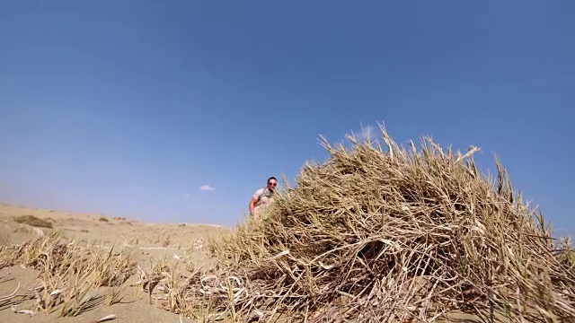 年轻的肌肉男在沙丘上做后空翻视频素材