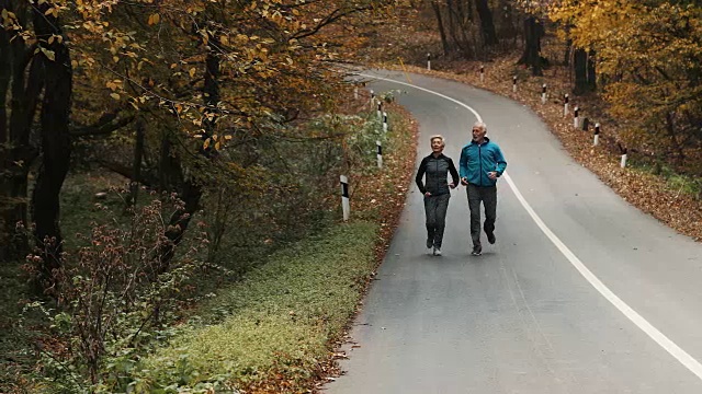 一对老年夫妇在森林里慢跑。视频素材