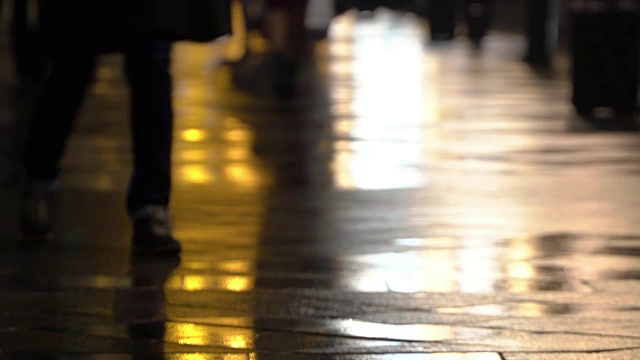在潮湿的人行道上，街灯映出了辨认不出的人的剪影。长长的影子。雨夜的城市街道上有路灯，沥青路从雨中闪闪发光。不认识的行人，年轻人。夜晚的城市下雨。购物的概念视频下载