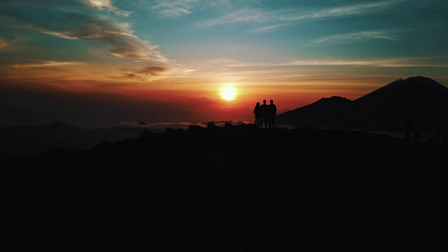 人们站在巴图尔活火山山顶上，在日出时，云层显示空中拍摄4K视频素材