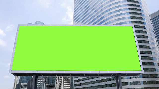 繁忙的一天，商务区办公楼前的空白绿色屏幕模拟广告牌，时间流逝。广告背景素材视频下载
