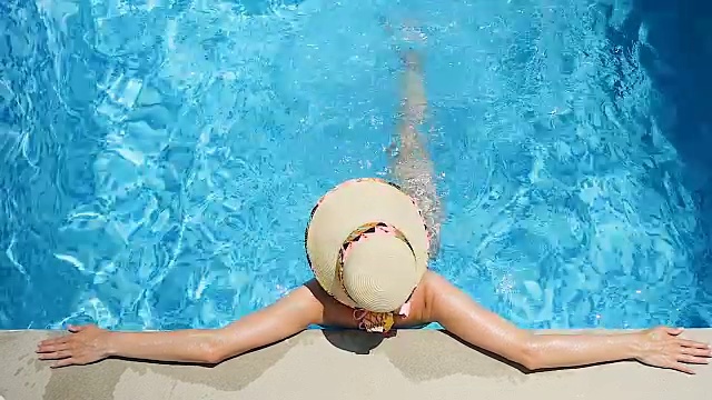 无忧无虑的女人放松在游泳池和踢水视频素材