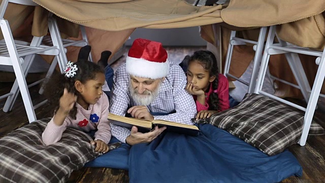 爷爷戴着圣诞帽和孩子们一起看书视频素材