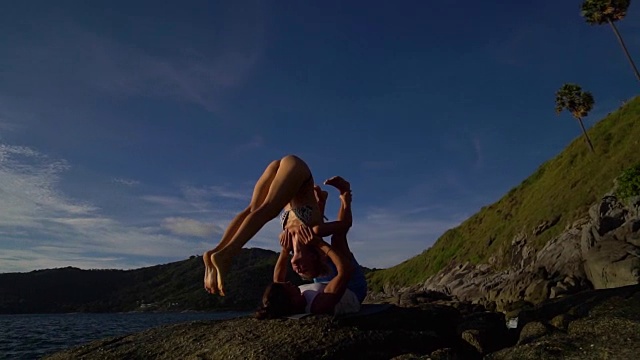 日落时分，在海边海滩的岩石上进行瑜伽练习。视频素材