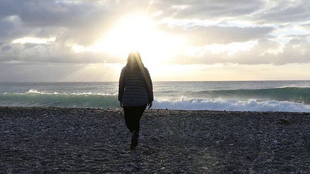 女人走过空旷的海滩，望着大海，望着日出视频素材