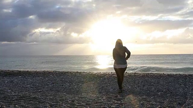 女人走过空旷的海滩，望着大海，望着日出视频素材
