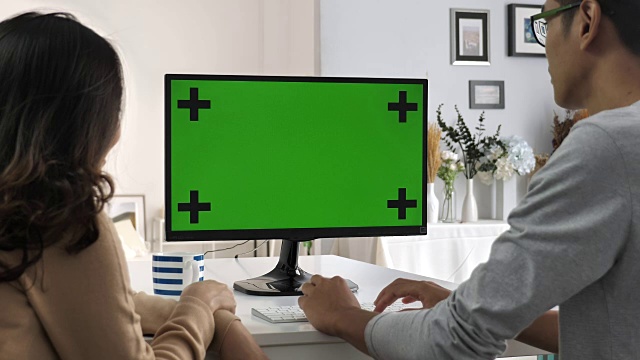两个亚洲人在和电脑屏幕对话，绿色屏幕，色度键视频素材