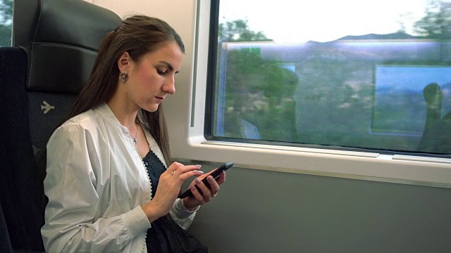 一位年轻女士在火车上使用智能手机视频素材