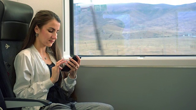 一位年轻女士在火车上使用智能手机视频素材