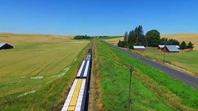 航拍追逐在麦田里运送谷物的火车。视频下载