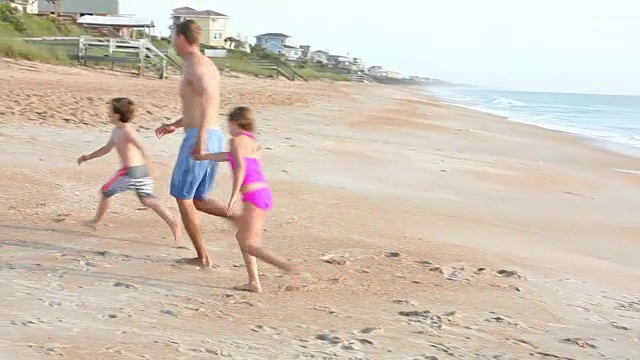 父亲和两个孩子在沙滩上冲浪视频素材