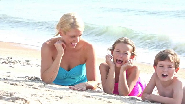 一家人躺在沙滩上对着镜头笑成一排视频素材