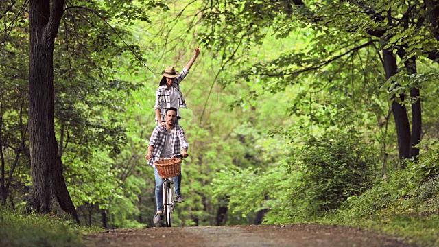 年轻的无忧无虑的夫妇有乐趣，而骑自行车通过森林。视频下载