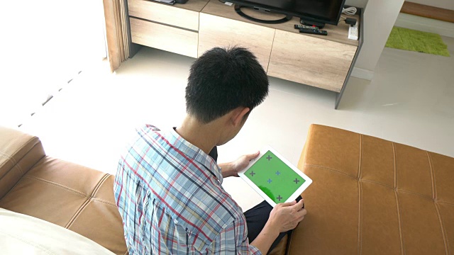 一个人在玩绿色屏幕的数字平板电脑视频素材