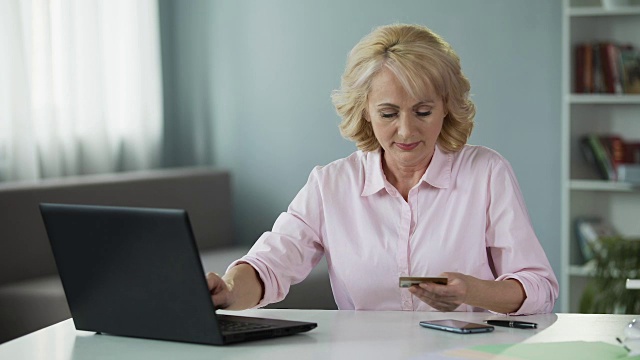 50岁以上的女人输入她的卡数据，在线支付公用事业服务视频素材
