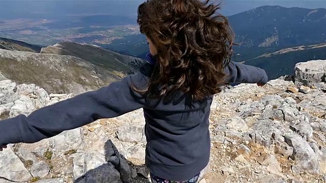小女孩在高高的山上举起双臂，慢动作视频素材