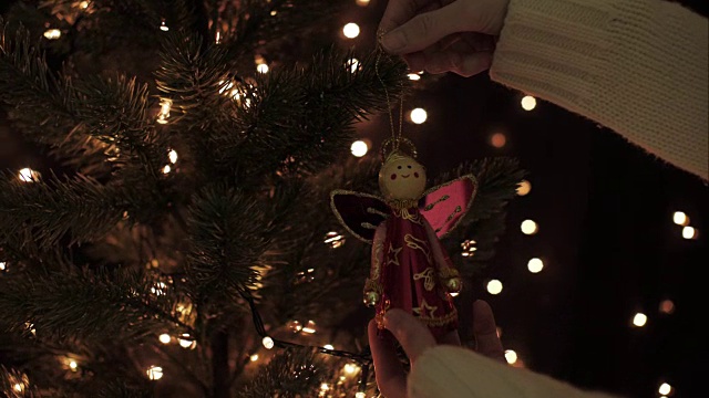 女人装饰仙女花环在圣诞树上与照明散景灯的背景视频素材