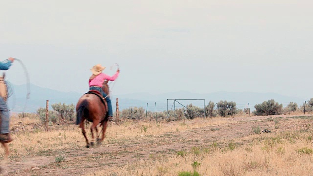 牛仔和女牛仔在一条土路上骑马视频素材