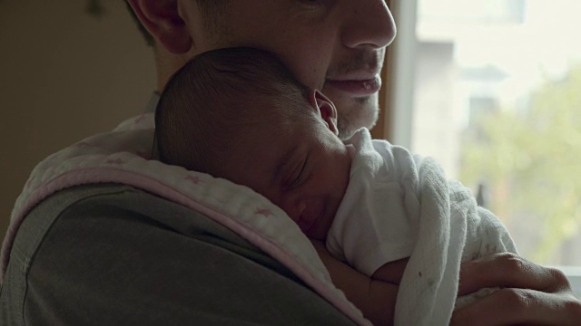 刚出生的婴儿微笑着，他的父亲抱着他视频素材