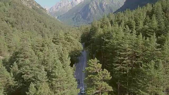 鸟瞰图上的汽车行驶在绿色森林的道路上的山脉背景视频素材