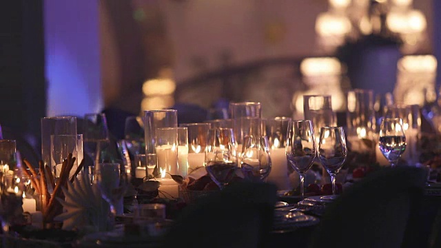 装饰蜡烛在餐桌上，眼镜和圣诞蜡烛在桌子上，白色蜡烛与玻璃烛台，蜡烛与玻璃烛台，餐厅，室内，特写视频素材
