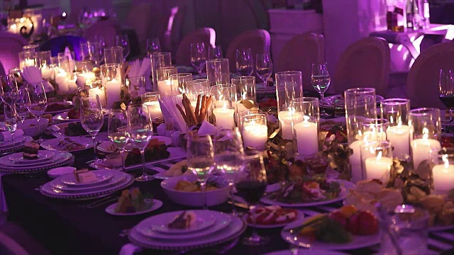 装饰蜡烛在餐桌上，眼镜和圣诞蜡烛在桌子上，白色蜡烛与玻璃烛台，蜡烛与玻璃烛台，餐厅，室内，特写视频下载