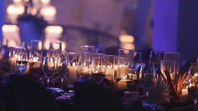装饰蜡烛在餐桌上，眼镜和圣诞蜡烛在桌子上，白色蜡烛与玻璃烛台，蜡烛与玻璃烛台，餐厅，室内，特写视频素材