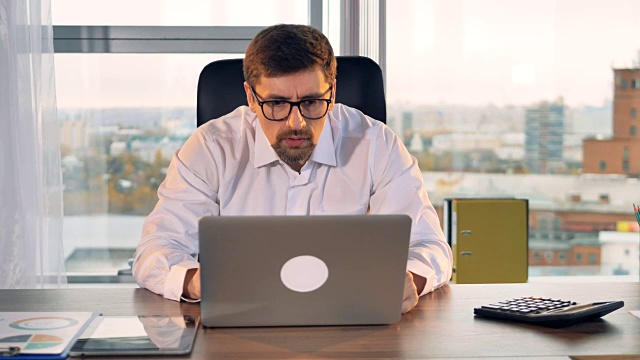 一个商人盯着笔记本电脑屏幕上的字体视图。视频素材