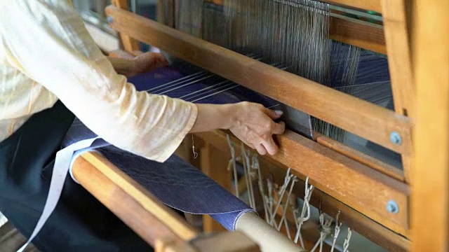 一个女人的手编织织物的特写，通过梭子来回视频素材