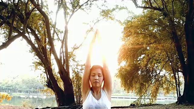日落时分，亚洲女性在湖边练习瑜伽视频素材