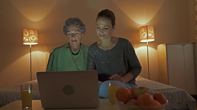 中年妇女和她的母亲通过笔记本电脑视频聊天，并向某人挥手。视频素材