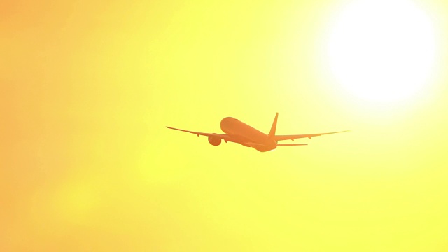剪影飞机飞过明亮的夕阳在惊人的金色日落视频素材