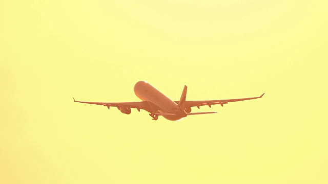 近距离观察日出时，一架客机在明亮的金色天空下飞行视频素材