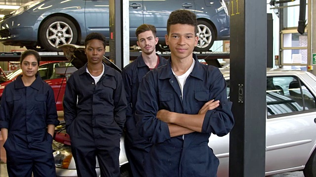 一群多种族的大学学徒在汽车车间穿着连衫裤套装视频下载